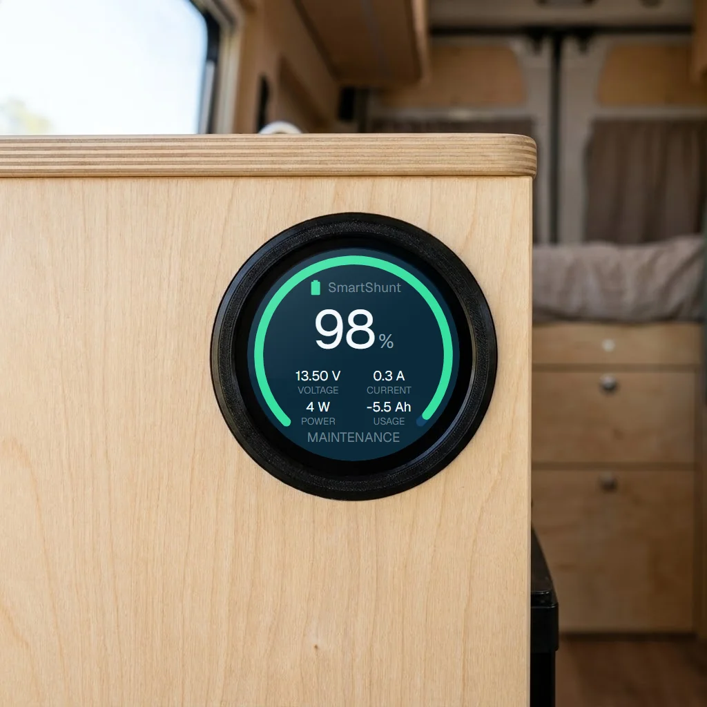 Voltvik device recessed into a plywood front in a campervan, with the battery page on the screen: 98 %, 13.50 V, 0.3 A and status MAINTENANCE
